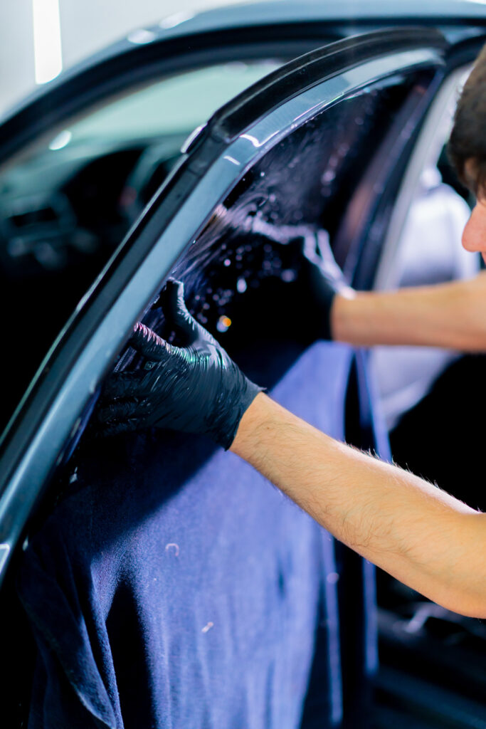 Steve Koulis Smash Repairs technician applying protective tinted film to car window