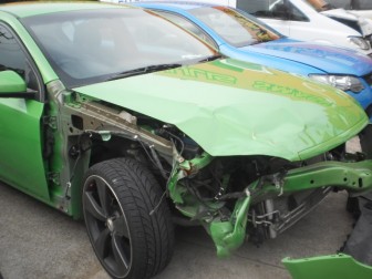 Damaged green Ford sedan before panel beating at Steve Koulis Smash Repairs