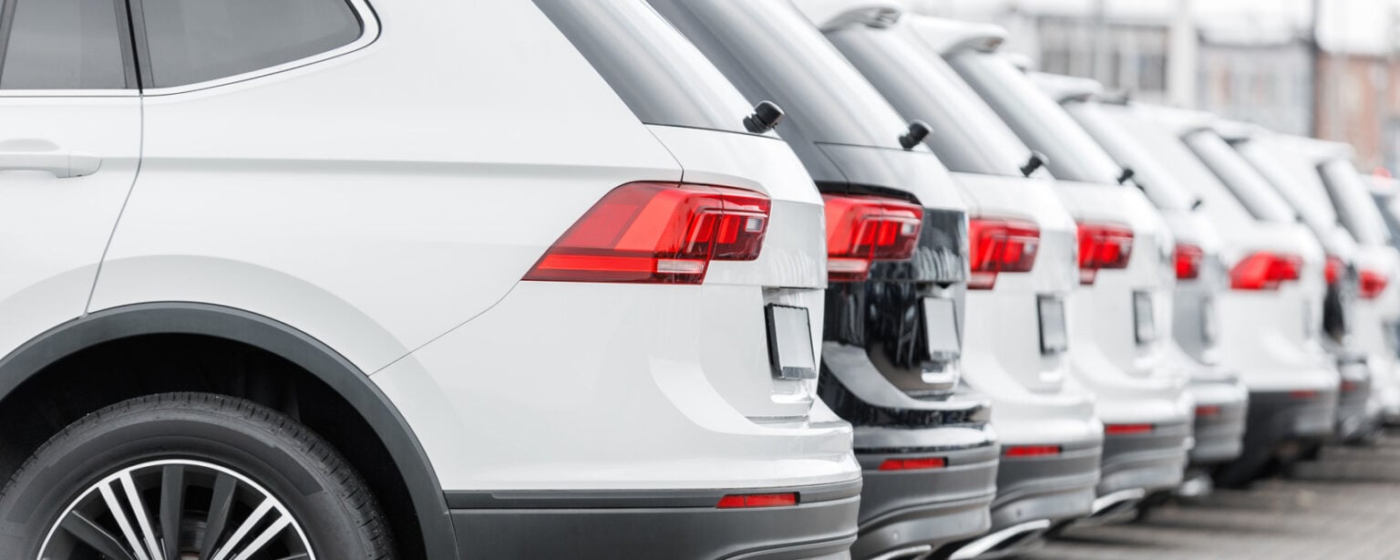 Row of new white SUVs parked in automotive storage lot at Steve Kouli Smash Repairs