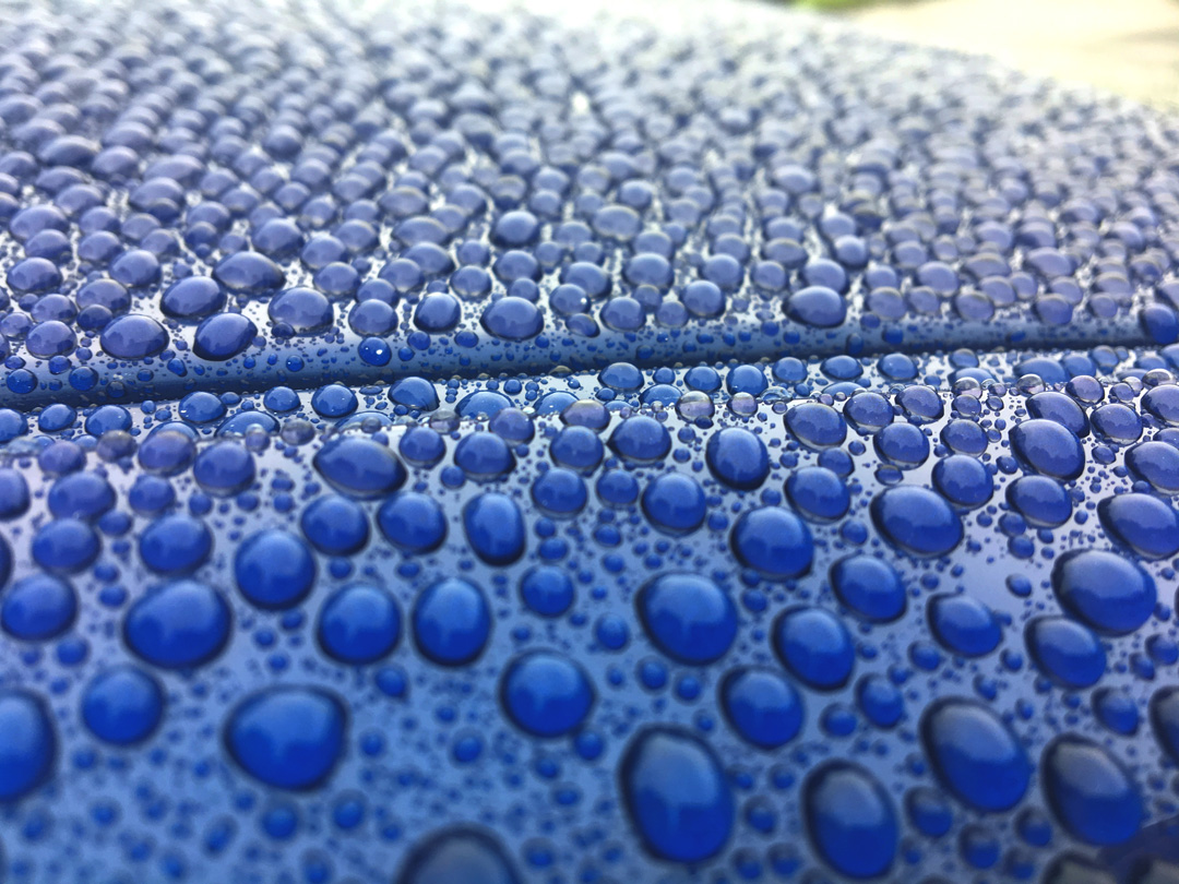 Close-up of water droplets on blue car body polished with ceramic coating at Steve Kouli Smash Repairs