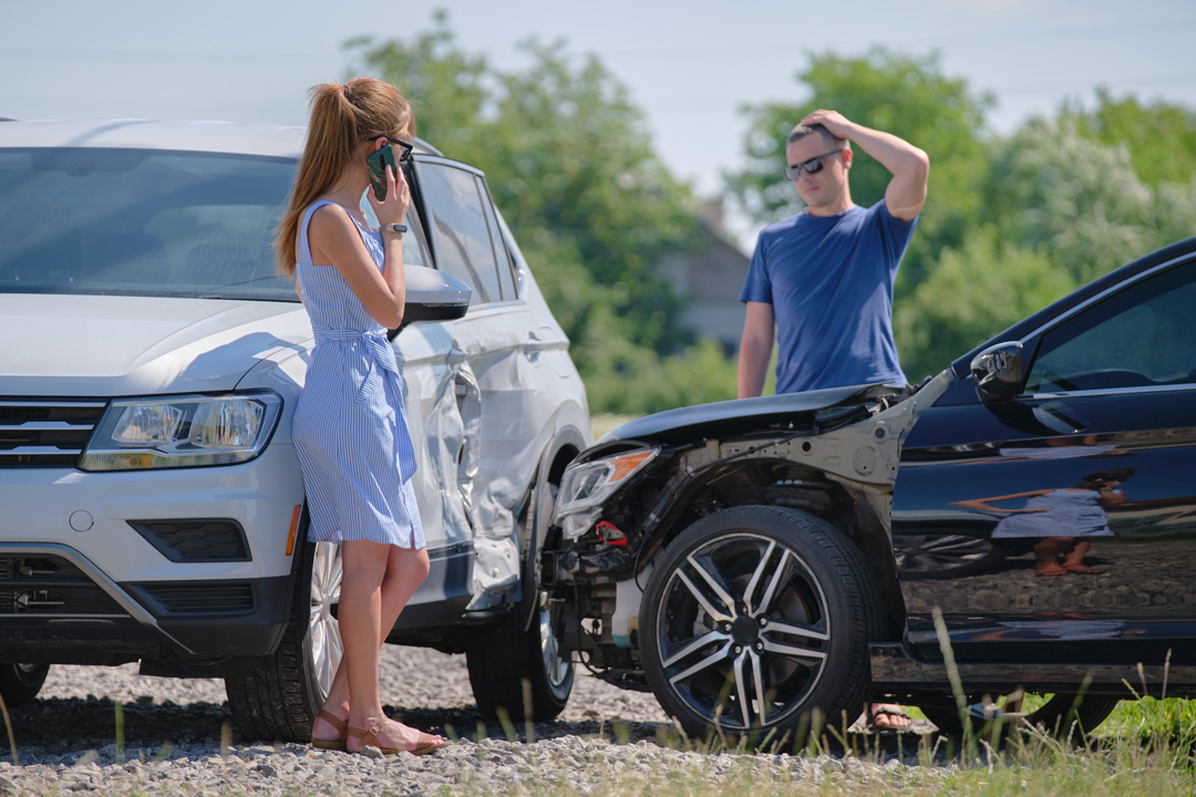 Man and woman beside damaged cars after accident for Steve Koulis Smash Repairs