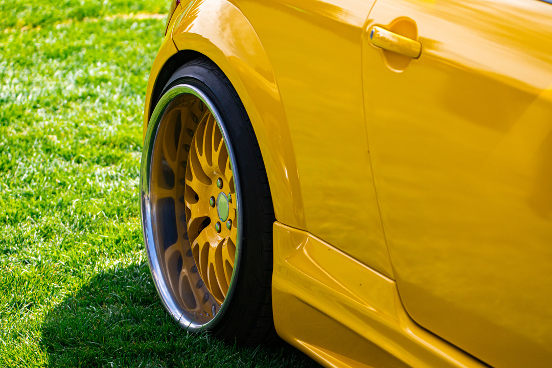 Close-up of yellow sports car rear wheel on grass at Steve Kouli Smash Repairs
